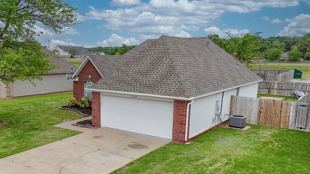 view of home's exterior featuring a shingled roof, central air condition unit, fence, a yard, and brick siding