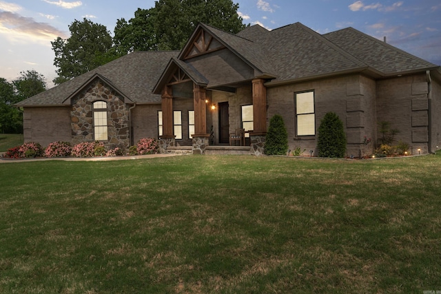 craftsman inspired home featuring a front lawn, stone siding, and roof with shingles