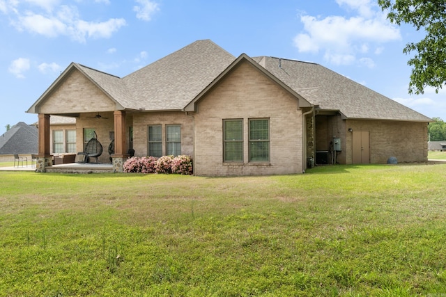 back of house with a lawn, brick siding, ceiling fan, and roof with shingles