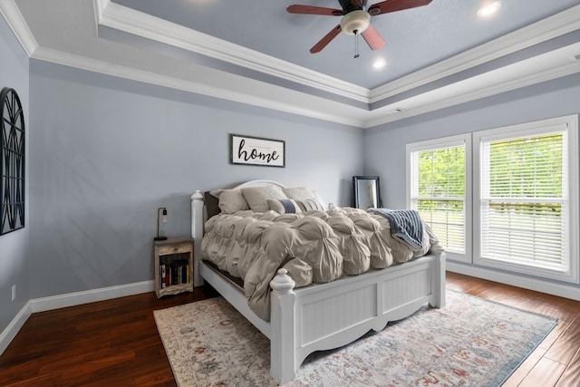 bedroom featuring wood finished floors, a raised ceiling, and ornamental molding