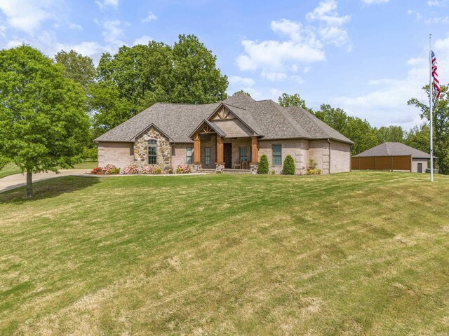 craftsman house with roof with shingles, covered porch, a front lawn, and stone siding