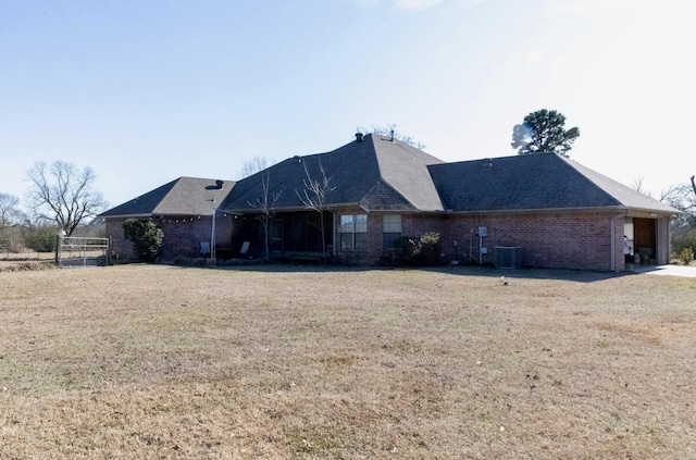 rear view of property with brick siding, cooling unit, and a lawn