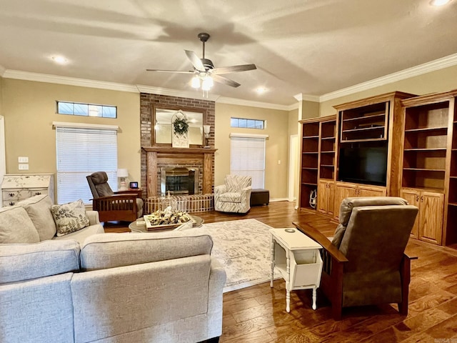 living room with dark wood finished floors, a ceiling fan, crown molding, and a brick fireplace