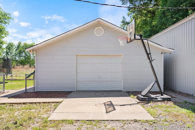 detached garage featuring a trampoline and driveway