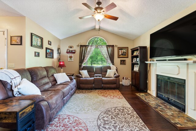 living room featuring a fireplace with flush hearth, a textured ceiling, dark wood-style floors, vaulted ceiling, and a ceiling fan