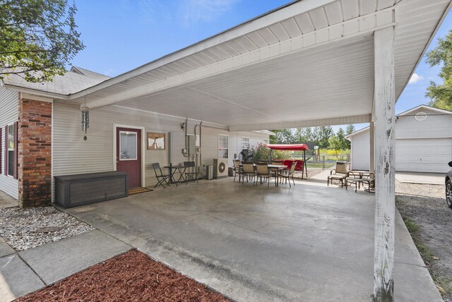 view of patio with outdoor dining space, a carport, and an outbuilding