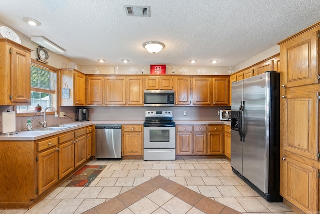 kitchen featuring a sink, stainless steel appliances, light tile patterned flooring, visible vents, and light countertops