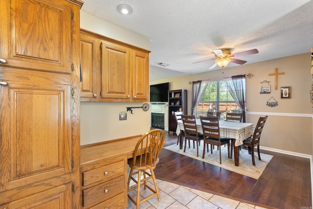 dining area featuring a ceiling fan, wood finished floors, and a textured ceiling