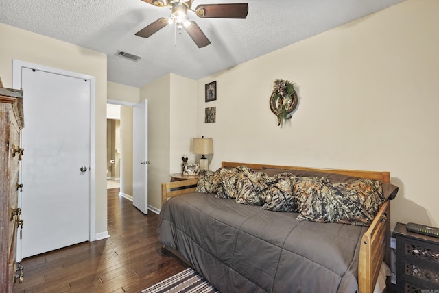 bedroom featuring hardwood / wood-style floors, visible vents, a textured ceiling, and baseboards