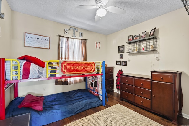 bedroom with a textured ceiling, ceiling fan, and dark wood-type flooring