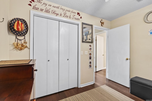 bedroom with dark wood-style floors, a closet, a textured ceiling, and baseboards