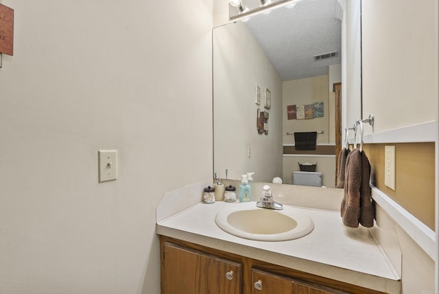 bathroom featuring a textured ceiling, visible vents, and vanity