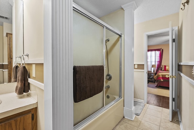 bathroom with a textured ceiling, connected bathroom, enclosed tub / shower combo, tile patterned floors, and vanity