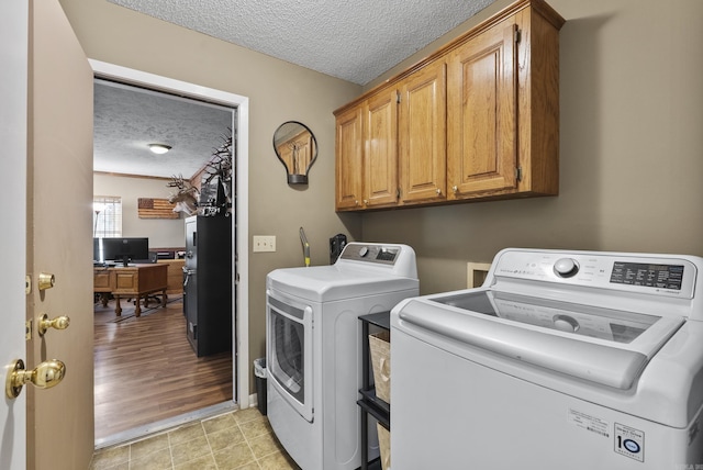 clothes washing area with a textured ceiling, cabinet space, and independent washer and dryer