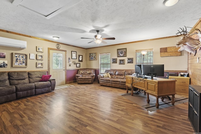 living room with a wainscoted wall, a wall unit AC, a ceiling fan, and wood finished floors