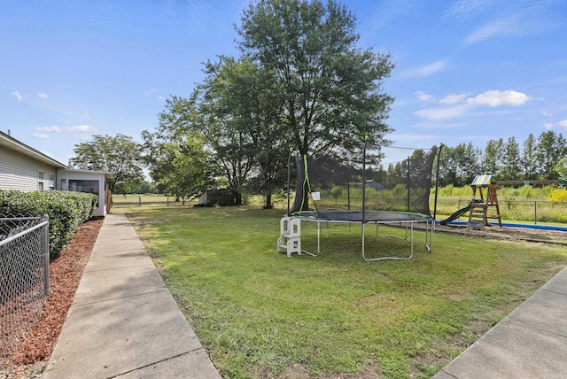 view of yard with fence, playground community, and a trampoline