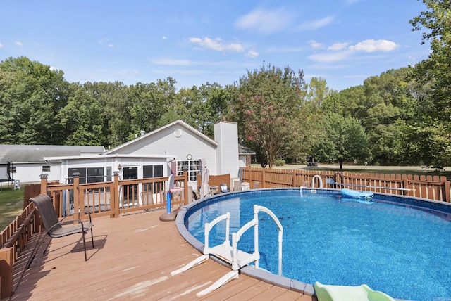 view of swimming pool featuring fence, a sunroom, a wooden deck, and a fenced in pool