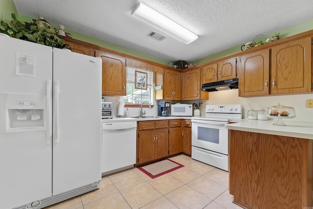 kitchen featuring white appliances, under cabinet range hood, light countertops, brown cabinets, and a sink