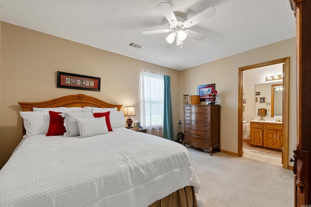 bedroom featuring connected bathroom, ceiling fan, visible vents, a textured ceiling, and light colored carpet