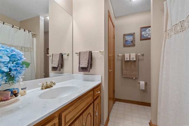 bathroom with tile patterned floors, a textured ceiling, vanity, and baseboards
