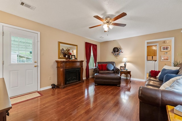 living area with wood finished floors, ceiling fan, a fireplace, baseboards, and visible vents