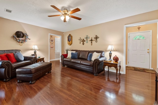 living area with baseboards, visible vents, wood finished floors, and a ceiling fan