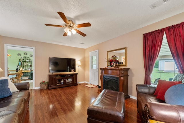 living room with baseboards, visible vents, wood finished floors, and ceiling fan