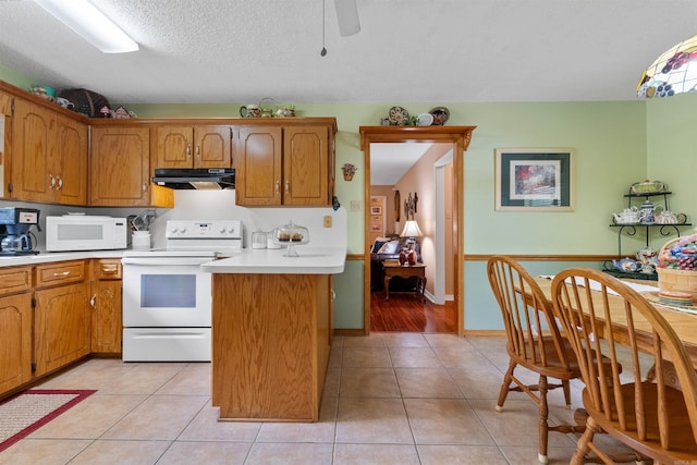 kitchen with white appliances, light countertops, brown cabinetry, and under cabinet range hood