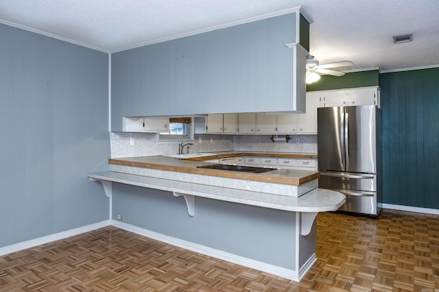kitchen featuring a sink, ceiling fan, a peninsula, light countertops, and freestanding refrigerator