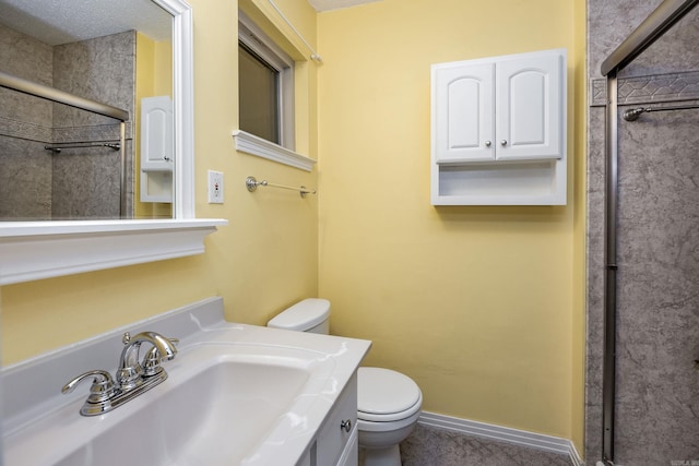 bathroom with toilet, a shower, vanity, and baseboards