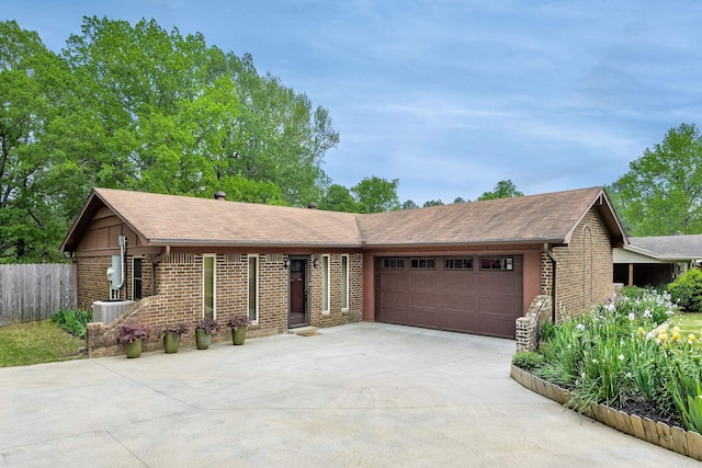 single story home with driveway, roof with shingles, brick siding, and a garage