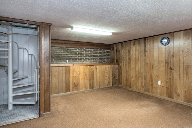 finished basement featuring wood walls, a textured ceiling, and carpet