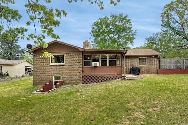 rear view of house with fence, a chimney, a lawn, and brick siding