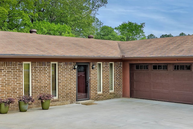 ranch-style home with concrete driveway, a shingled roof, brick siding, and a garage