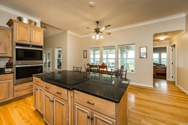 kitchen with plenty of natural light, light wood-style floors, crown molding, and double oven
