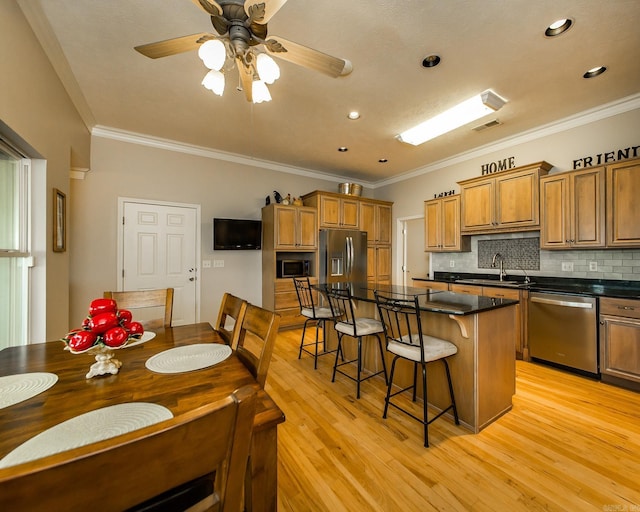kitchen with appliances with stainless steel finishes, a kitchen bar, ornamental molding, and brown cabinetry