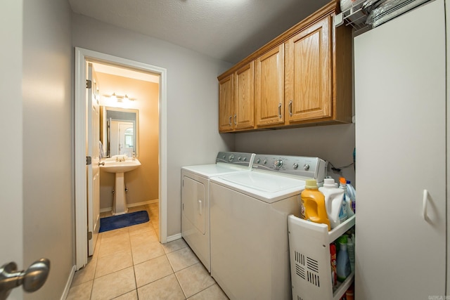 laundry room with light tile patterned floors, cabinet space, washing machine and clothes dryer, and baseboards