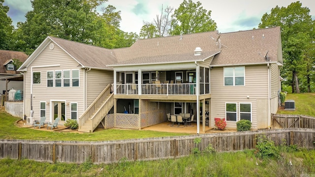 back of property with stairs, a patio area, roof with shingles, a sunroom, and a fenced backyard
