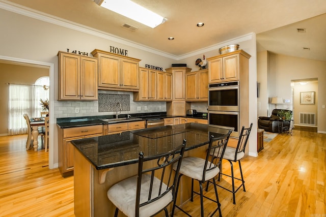 kitchen featuring a sink, a kitchen bar, visible vents, and stainless steel appliances