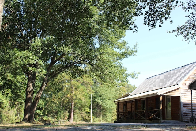 view of side of property with a porch, log veneer siding, and metal roof
