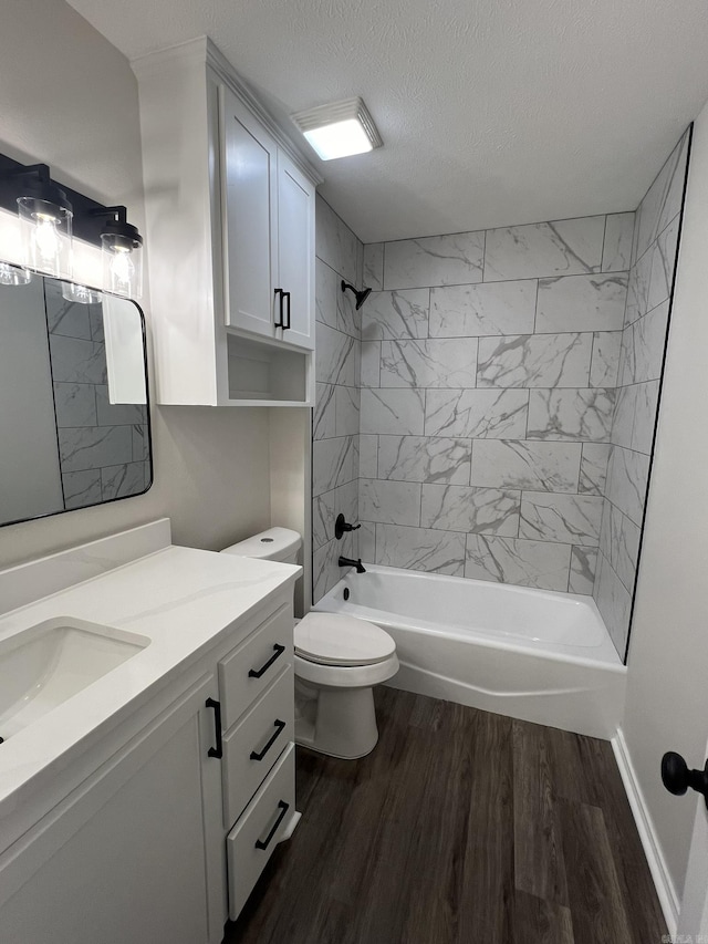 bathroom featuring wood finished floors, toilet, shower / tub combination, vanity, and a textured ceiling