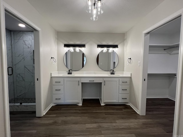 full bath with a sink, a shower stall, wood finished floors, and a spacious closet