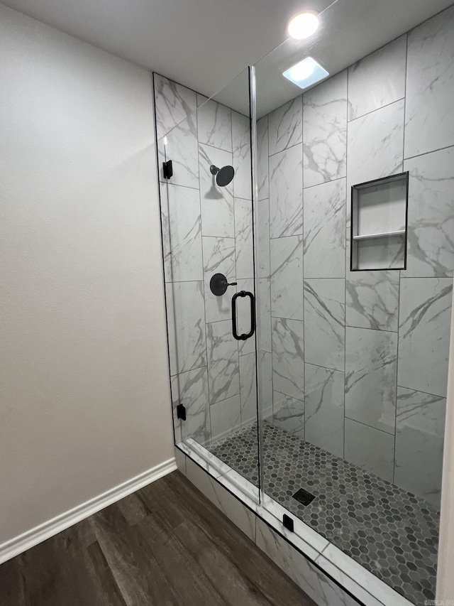 bathroom featuring wood finished floors, a stall shower, and baseboards