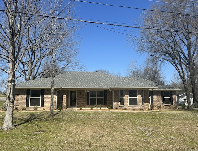 view of front of home featuring brick siding, a front lawn, and roof with shingles