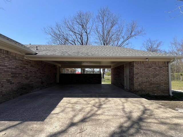 view of parking with driveway and an attached carport