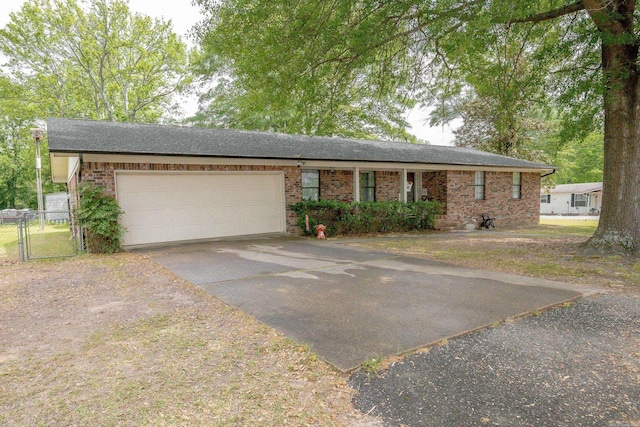 ranch-style home with concrete driveway, an attached garage, brick siding, and a gate