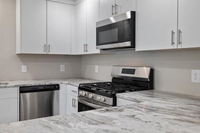 kitchen featuring white cabinets, appliances with stainless steel finishes, and light stone counters