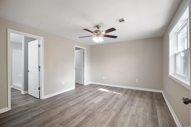 unfurnished bedroom with baseboards, visible vents, wood finished floors, and ceiling fan