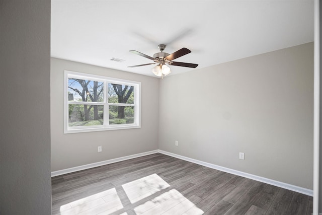 empty room featuring baseboards, visible vents, ceiling fan, and dark wood-type flooring