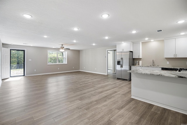 kitchen with light wood-style flooring, ceiling fan, white cabinetry, visible vents, and stainless steel refrigerator with ice dispenser